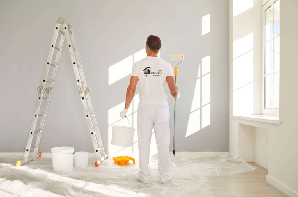 Mitarbeiter mit Rolle und Farbeimer vor der Wand, die er streicht.